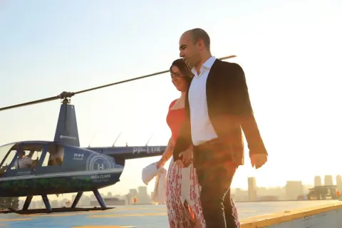Casal caminhando junto ao helicóptero na luz do pôr do sol
