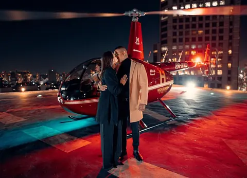 Casal junto ao helicóptero à noite no heliponto